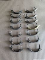Fourteen curved cabinet pulls arranged in two columns on cardboard