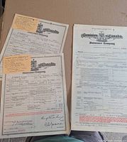 Three vintage Dominion Insurance Company documents laid on cardboard, showing text, signatures and orange claim stubs