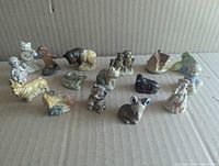 All sixteen Wade Whimsies figurines arranged on cardboard backdrop