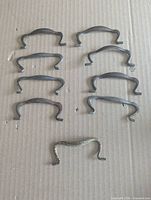Nine curved steel drawer pulls arranged on cardboard