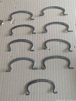 Nine steel omega-shaped drawer pulls laid out