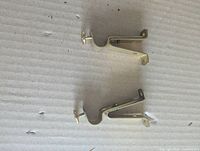 Two adjustable brass curtain rod brackets side view showing mounting holes and adjustment screws