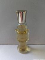 Front view of clear glass soldier-shaped perfume bottle with silver cap and visible perfume level