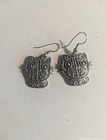 Front view of pewter cat face dangle earrings showing design and hooks
