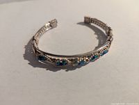 Front view of silver-tone wire wrapped cuff bracelet showing blue bead detailing