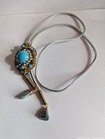 Front view of bolo tie showing cabochon, bead accents, cord and stone tips