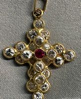 Front view of gold crucifix pendant showing ruby center and surrounding cubic zirconias