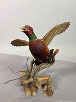 Front view of porcelain pheasant with wings spread on branch base