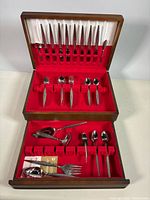 Open wooden chest showing full flatware set in red felt slots