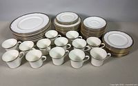 Complete dish set laid out: stacks of plates, saucers, cups, oval platters