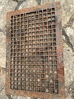Top view of rectangular cast iron grate showing grid pattern and rust