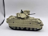 Left side view of desert tan model tank with crew figure and turret