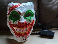 Front of mask unlit showing paint details and attached battery pack