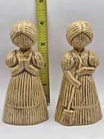 Front view of both speckled ceramic figurine shakers with measuring tape for height reference