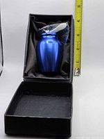 Urn in open presentation box beside ruler