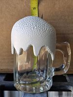 Front view showing glass mug and textured foam lid with tape measure for scale