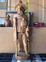 Front view of wooden traveler sculpture with tape showing height