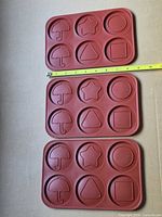 Three identical red silicone molds showing cavity shapes