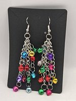 Front view of earring pair on display card, showing multicolor bell charms and chain tassels