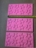 Front view of three pink silicone molds showing star cavities and measuring tape for scale
