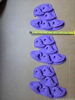 Three purple silicone witch-hat molds laid vertically with tape measure for scale