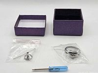 Lot overview showing ring in bag, box lid and base, screwdriver, funnel kit
