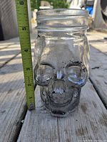 Front view of clear skull jar with measuring tape indicating height
