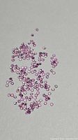 Bulk view of loose pink sapphires scattered on surface