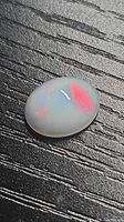 Top view of oval cabochon opal showing red and green fire