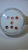 Seven round padparadscha sapphires in gem jar frontal view