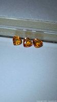 Three heart-cut orange sapphires on gem card