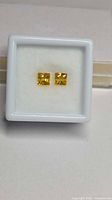 Pair of square yellow sapphires in display box, front view