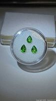 Three vivid green pear-cut tsavorite garnets in round display case