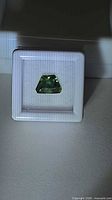 Front view of trapezoid-cut green sapphire in display box
