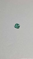 Emerald on flat surface showing cushion shape and color