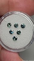 Six aqua blue round sapphires in display case top view