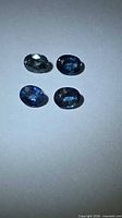Four oval blue sapphires on white background