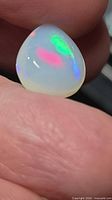 Front view of pear cabochon opal showing vivid colour play