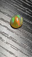 Top view of oval Ethiopian caramel opal displaying multicolour play-of-colour