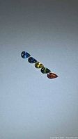 Five multicolored pear-cut sapphires lined up on white background