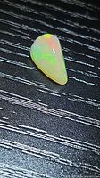 Freeform pear cabochon opal showing green play-of-color