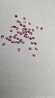 Loose bright pink faceted garnets scattered on neutral background