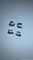 Four pear-cut light blue aquamarines on neutral background