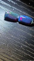 Pair of rectangular faceted black opals showing play-of-colour