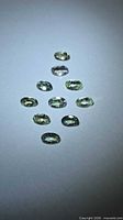 Ten oval lemon lime tanzanites arranged on neutral background