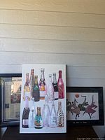 All three art pieces: canvas with bottles, framed newspaper print, framed dancer print