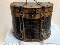 Front view of trunk showing leather panels, latch, straps, rivets