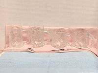 Group view of four clear embossed glass mugs