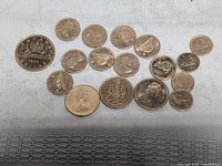 All 16 coins laid out on cloth showing obverses and reverses