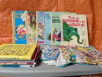 Group of standing and stacked children's books with sticker packets spread on table